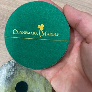 May include: A green round coaster with a gold shamrock and the text "Connemara Marble" in gold lettering.