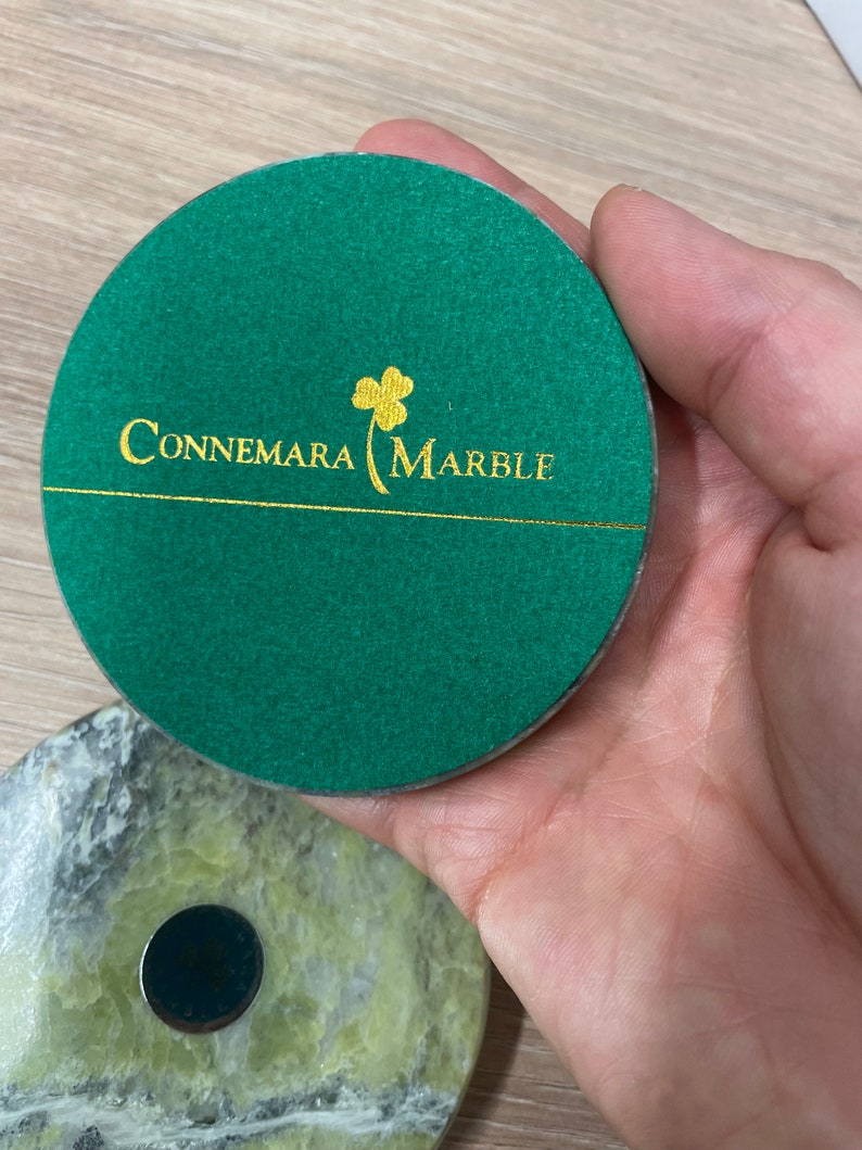 May include: A green round coaster with a gold shamrock and the text "Connemara Marble" in gold lettering.