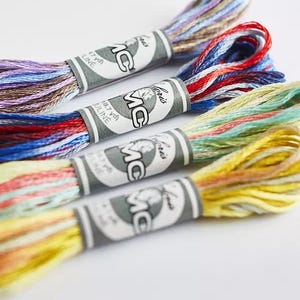 May include: Four spools of DMC embroidery floss in a variety of colours, including blue, red, yellow, and green. Each spool has a white label with the DMC logo and the text "DMC Iris" printed on it.