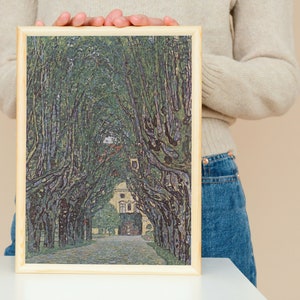 May include: A framed painting of a tree-lined path leading to a building. The trees are green and the path is gray. The building is white with a brown roof.