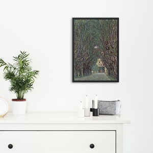 May include: A framed painting of a tree-lined path leading to a building. The trees are green and the building is yellow. The painting is in a black frame.
