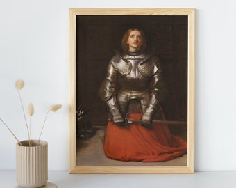 May include: A painting of a woman in a silver suit of armor kneeling with a sword in her hands. She is looking up with a sorrowful expression. The background is dark and the painting is framed in a light wood frame.