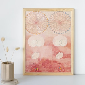 May include: A framed print of a painting featuring two large pink and white circles, surrounded by smaller circles and shapes. The background is a soft pink and red.