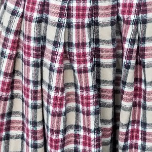 May include: A beige, red, white, and black plaid skirt with pleats.