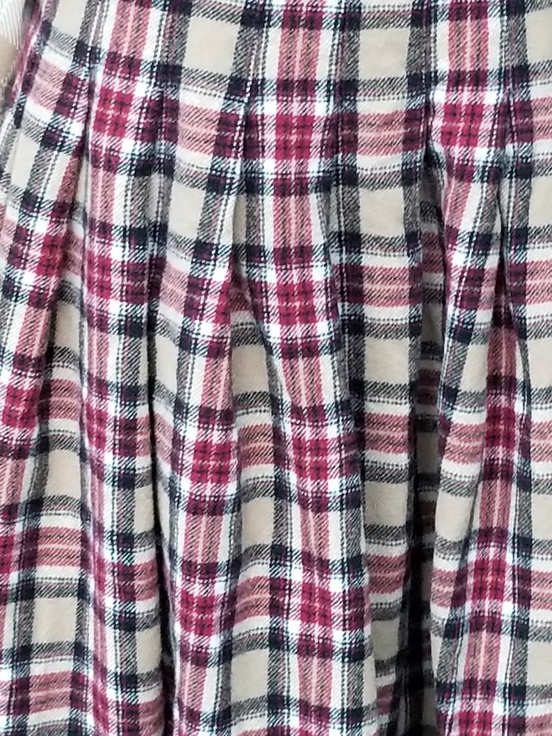 May include: A beige, red, white, and black plaid skirt with pleats.