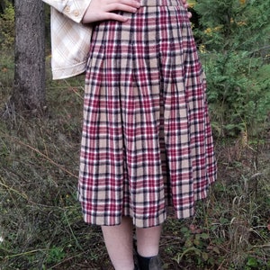 May include: A brown, red, and white plaid skirt with pleats. The skirt is knee-length and has a fitted waist.