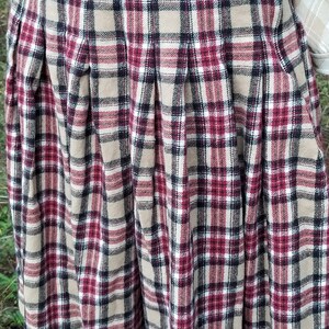 May include: A pleated skirt with a plaid pattern in shades of brown, red, black, and white.