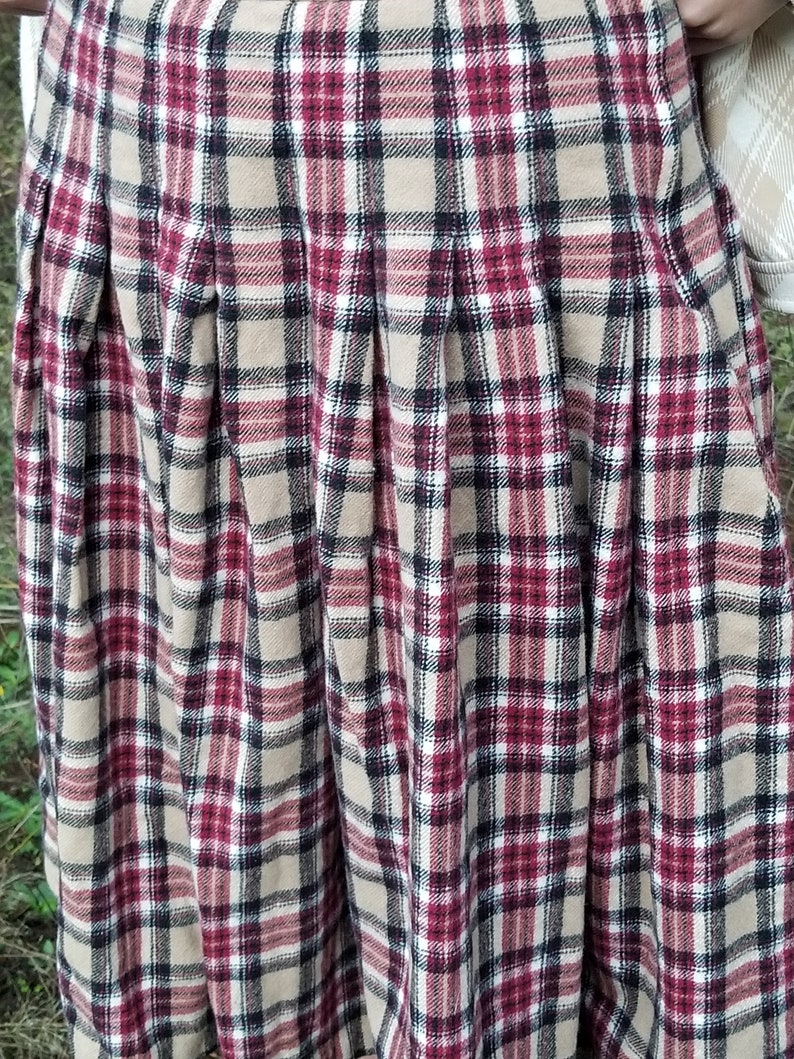 May include: A pleated skirt with a plaid pattern in shades of brown, red, black, and white.