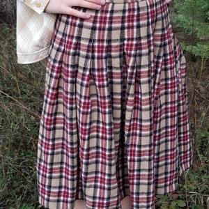 May include: A brown, red, and black plaid skirt with pleats. The skirt is knee-length and has a fitted waist.