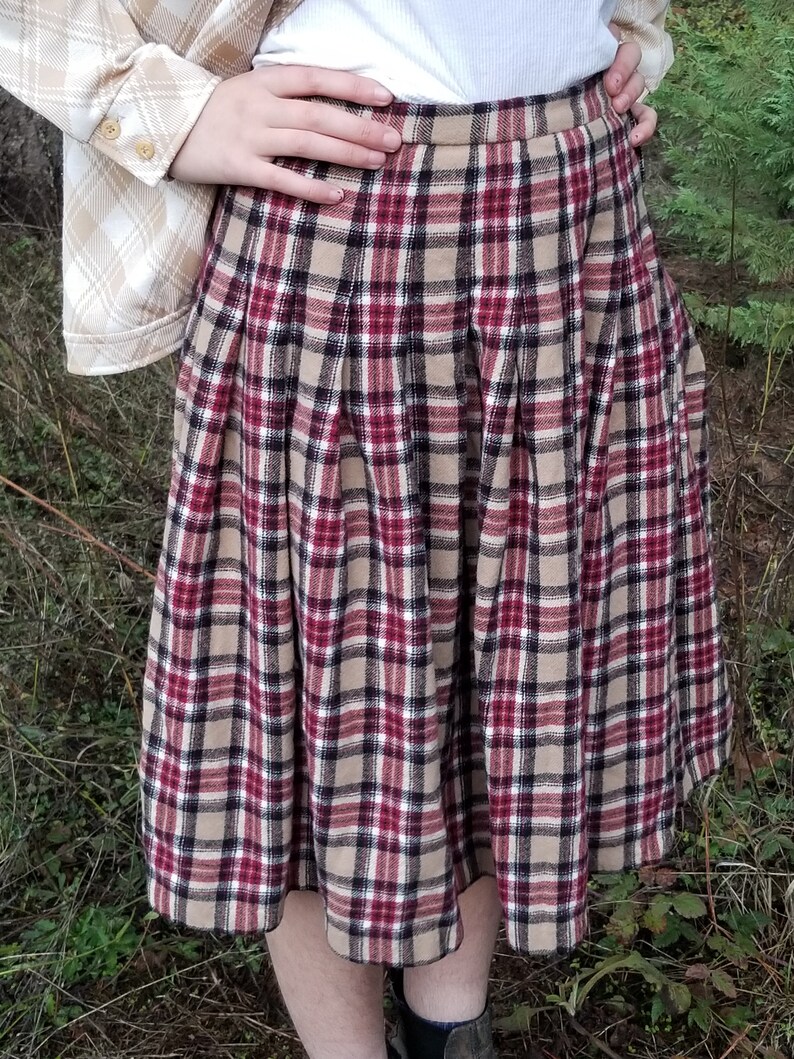May include: A brown, red, and black plaid skirt with pleats. The skirt is knee-length and has a fitted waist.