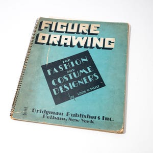 Könnte beinhalten: Ein Vintage-Buch mit Spiralbindung mit dem Titel "FIGURE DRAWING" mit Text in weißen Blockbuchstaben. Darunter steht in einem schwarzen Quadrat "FOR FASHION AND COSTUME DESIGNERS". Das Buch hat einen türkisfarbenen Einband und stammt von Bridgman Publishers.