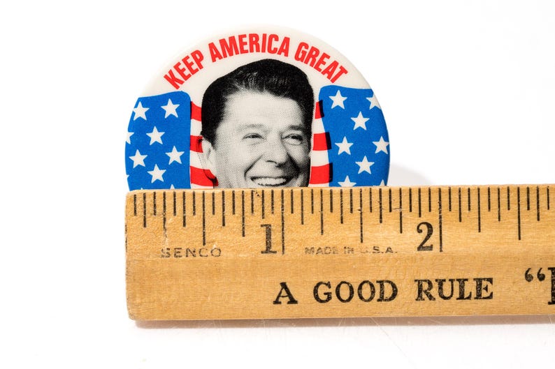 May include: A white ceramic mug with a black handle and the text "But First, Coffee" in a black, handwritten-style font. The mug is on a white surface.