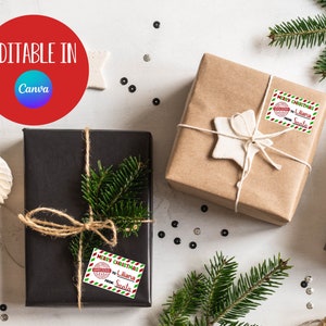 May include: Two brown gift boxes wrapped with twine and decorated with a white star and green pine branches. Each box has a red and green Christmas gift tag with the text "Merry Christmas to Liliana from Santa".
