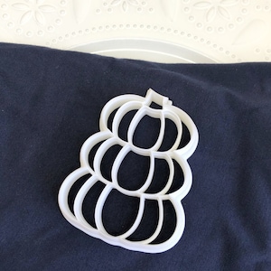 May include: White plastic cookie cutter shaped like a stack of pumpkins.
