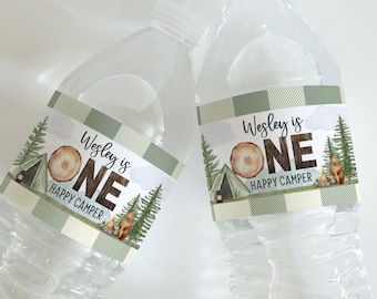 May include: Two clear plastic water bottles with green and white labels that say "Wesley is One Happy Camper". The labels have a brown and white wood grain design with a tent and trees.