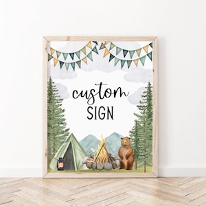 May include: A printable sign with a woodland theme. The sign features a campfire, a tent, a bear, and trees. The text on the sign reads "custom sign".