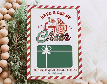May include: A red and white striped card with a green gift card in the center. The card has a festive design with a snowman and a cup of hot chocolate. The text on the card reads "Have a Cup of Cheer" and "Thanks so much for all you do! -The Harrison's-."