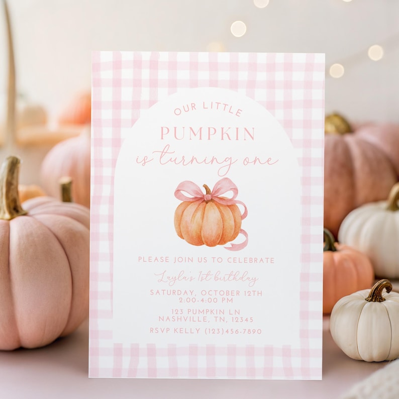 May include: A pink and white checked invitation card with the words "Our Little Pumpkin is turning one." The card has a watercolour illustration of a pumpkin with a pink bow. Further text provides party details.