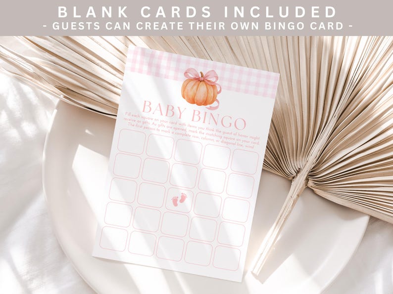 May include: A Baby Bingo card with a pumpkin illustration and pink gingham pattern. The card includes blank spaces for guests to fill in. The text "Baby Bingo" is at the top of the card.
