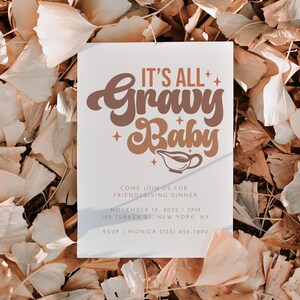 Op de afbeelding: Een witte uitnodigingskaart met bruine en oranje tekst die "It's All Gravy Baby" luidt. De kaart is versierd met kleine sterren en een sausbootpictogram. De tekst onder de titel luidt "Come join us for Friendsgiving Dinner, November 19, 2022 / 5PM, 123 Turkey St. New York, NY. RSVP / Monica (123) 456-7890."