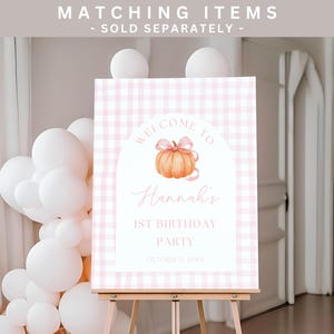Puede incluir: Un letrero de bienvenida a cuadros rosas para una fiesta de 1er cumplea&ntilde;os. El letrero presenta una calabaza de acuarela con un lazo rosa y el texto "Bienvenida a la 1&ordf; fiesta de cumplea&ntilde;os de Hannah". El letrero est&aacute; en un caballete de madera.
