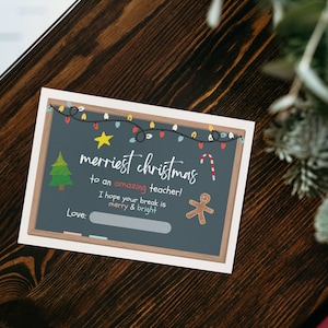 Peut inclure: Une carte de No&euml;l de style tableau noir avec un message festif qui dit "merriest christmas to an amazing teacher! I hope your break is merry & bright." La carte repr&eacute;sente un sapin de No&euml;l, une canne en sucre, un bonhomme en pain d'&eacute;pices et une guirlande lumineuse.