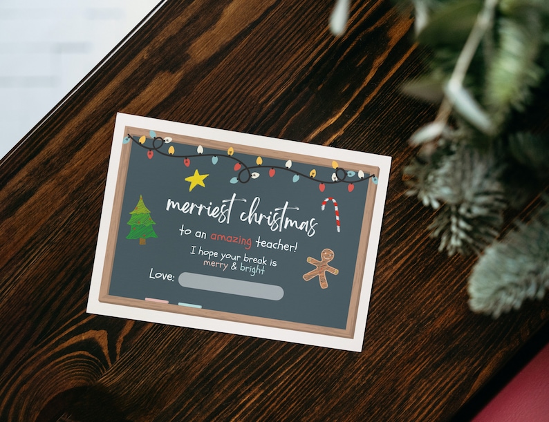 Peut inclure: Une carte de No&euml;l de style tableau noir avec un message festif qui dit "merriest christmas to an amazing teacher! I hope your break is merry & bright." La carte repr&eacute;sente un sapin de No&euml;l, une canne en sucre, un bonhomme en pain d'&eacute;pices et une guirlande lumineuse.