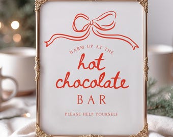 Può includere: Un cartello rettangolare in una cornice dorata con la scritta "Warm up at the hot chocolate bar" in rosso. Un fiocco rosso in alto. Il cartello dice anche "Please help yourself".