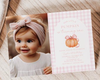 Può includere: Una bambina con una fascia rosa e un invito di compleanno. L'invito presenta un motivo a quadretti rosa e un'illustrazione di zucca con il testo "Our Little Pumpkin is turning one."