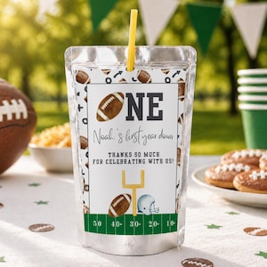 May include: A clear plastic pouch with a yellow straw, decorated with footballs and the text "ONE Noah's first year down". The pouch also features a football field graphic and the words "THANKS SO MUCH FOR CELEBRATING WITH US!"