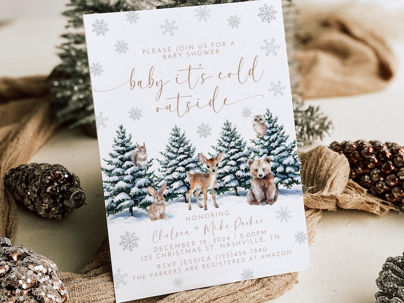 Puede incluir: Una invitaci&oacute;n de baby shower blanca con un tema de bosque de invierno. La invitaci&oacute;n presenta una ilustraci&oacute;n de acuarela de un bosque nevado con un ciervo, un oso, una ardilla, un b&uacute;ho y un conejo. El texto dice "baby it's cold outside" e incluye los nombres Chelsea y Mike Parker, la fecha y la hora de la ducha, y la direcci&oacute;n.