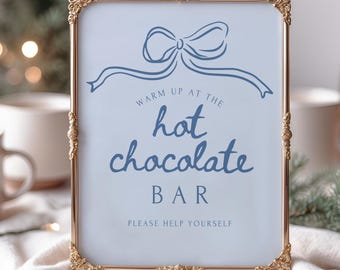 Può includere: Un cartello rettangolare con cornice dorata e angoli ornati. Il cartello ha uno sfondo azzurro con un'illustrazione di fiocco blu in alto. Il testo sul cartello recita: "Warm up at the hot chocolate bar. Please help yourself."
