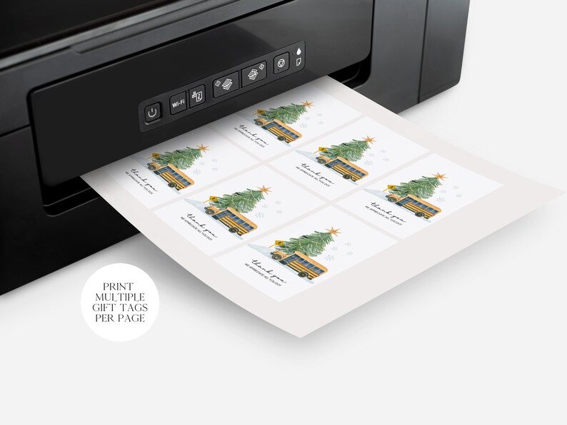May include: Printable gift tags featuring a yellow school bus with a Christmas tree on top. The tags say "Thank you" and are printed on white paper. The tags are being printed on a black and white printer.