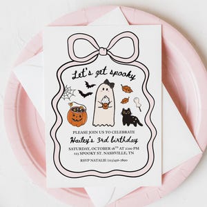May include: A Halloween-themed invitation with a pink bow design. The invitation features a ghost, black cat, pumpkin, and the text "Let's get spooky" and "Hailey's 3rd birthday". The invitation is on a pink plate.