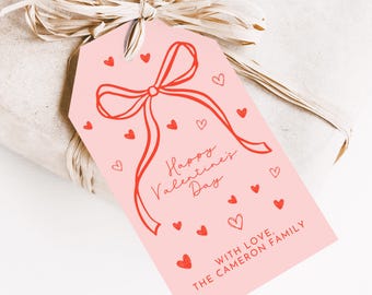 May include: Pink gift tag with a red bow and hearts. The text reads "Happy Valentine's Day" and "With love, The Cameron Family".