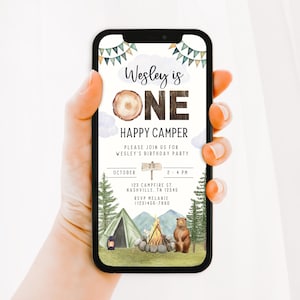 May include: A digital invitation for a first birthday party with a woodland camping theme. The invitation features a brown wooden number one, a bear, a campfire, and a tent. The text on the invitation reads "Wesley is One Happy Camper".