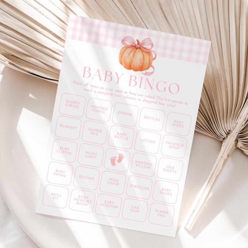May include: A baby bingo game card with a pink gingham pattern and a watercolor pumpkin illustration. The card features a grid of baby-related items like diapers, bottles, and a stroller. The text "BABY BINGO" is at the top.