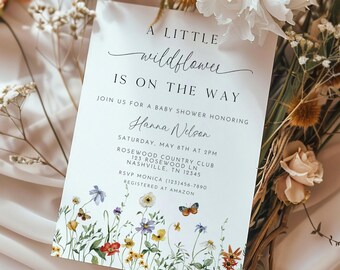Puede incluir: Una invitación de baby shower blanca con un diseño floral y el texto "A Little Wildflower Is On The Way". Únase a nosotros para una baby shower en honor a Hanna Nelson. Sábado, 8 de mayo a las 2:00 p. m. Rosewood Country Club, 123 Rosewood Ln, Nashville, TN 12345. RSVP Monica (123) 456-7890. Registrado en Amazon.