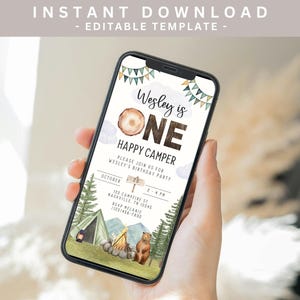 May include: A digital invitation for a first birthday party with a woodland theme. The invitation features a brown wooden sign with the text "Wesley is One" and a cartoon bear and tent. The text on the invitation reads "Happy Camper" and includes details for the party, including the date, time, and location.