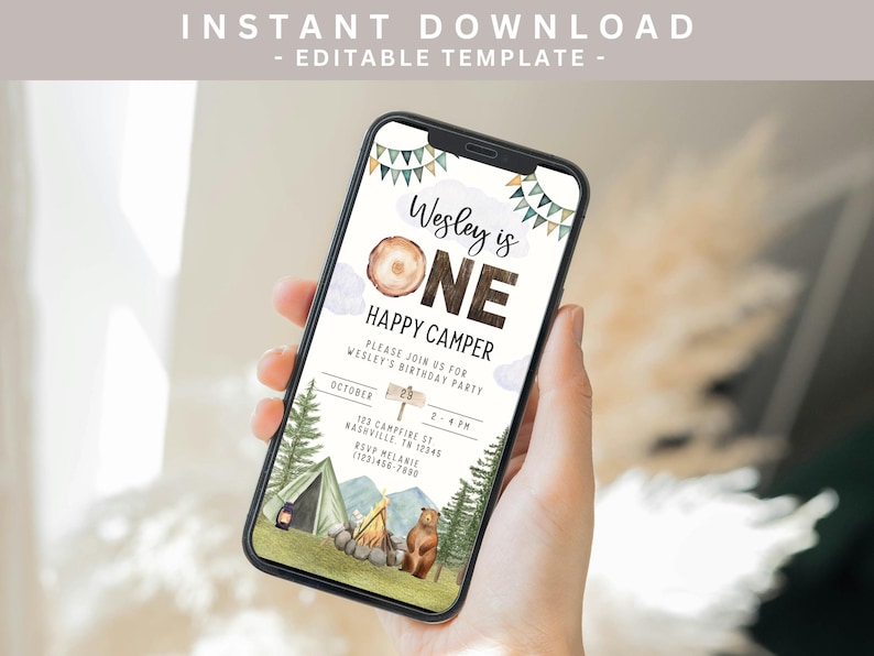 May include: A digital invitation for a first birthday party with a woodland theme. The invitation features a brown wooden sign with the text "Wesley is One" and a cartoon bear and tent. The text on the invitation reads "Happy Camper" and includes details for the party, including the date, time, and location.
