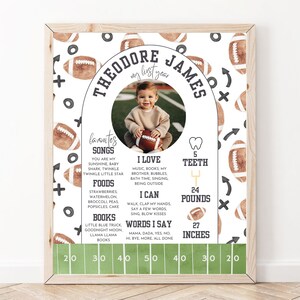 May include: A white and brown football-themed first birthday milestone poster with a photo of a baby boy. The poster includes the baby's name, Theodore James, and details about his first year, including his favorite songs, foods, books, and milestones like teeth, weight, and height.