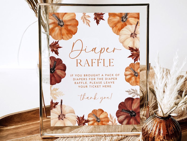 May include: A framed sign with a fall theme. The sign reads "Diaper Raffle" with watercolor pumpkins and leaves. The text below explains the raffle rules and includes a "thank you" message.