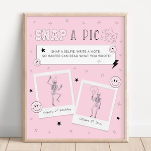 May include: Pink framed print with the text "SNAP A PIC" and a camera illustration. Includes two polaroid-style photos of skeletons, stars, and smiley faces. The text "SNAP A SELFIE, WRITE A NOTE, SO HARPER CAN READ WHAT YOU WROTE!" is also included.