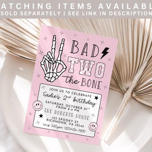 May include: A pink birthday invitation with the text "BAD TWO the BONE" and a skeleton hand making a peace sign. The invitation includes details for a second birthday party, including the date, time, and location.