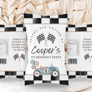 Può includere: Un sacchetto regalo a scacchi bianco e nero con un'auto da corsa blu e palloncini. Il sacchetto ha il testo "Grazie per aver corso con Cooper's 1° compleanno".