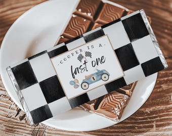 May include: A chocolate bar wrapper with a black and white checkered pattern. The wrapper has a label that says "Cooper is a - fast one" with a cartoon race car and checkered flags.