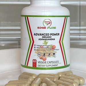 Może przedstawiać: Biała butelka z zielono-czerwoną etykietą, na kt&oacute;rej widnieje napis "EDGE PURE ADVANCED POWER ORGANIC ASHWAGANDHA" oraz "60 VEGGIE CAPSULES DIETARY SUPPLEMENT". Butelka stoi na białym tle, a obok niej znajduje się stos przezroczystych kapsułek.