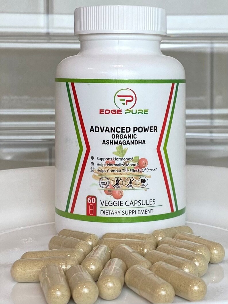 Może przedstawiać: Biała butelka z zielono-czerwoną etykietą, na kt&oacute;rej widnieje napis "EDGE PURE ADVANCED POWER ORGANIC ASHWAGANDHA" oraz "60 VEGGIE CAPSULES DIETARY SUPPLEMENT". Butelka stoi na białym tle, a obok niej znajduje się stos przezroczystych kapsułek.