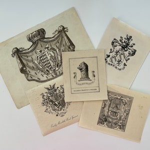 May include: A collection of antique black and white heraldic prints. The prints feature detailed crests, coats of arms, and illustrations of animals. Some prints include text, such as "EX LIBRIS FRANCIS N. MILLER" and names.