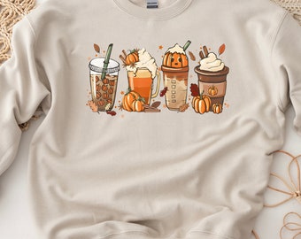 May include: A beige sweatshirt with a graphic of four fall-themed coffee drinks with pumpkin spice, whipped cream, and fall leaves.